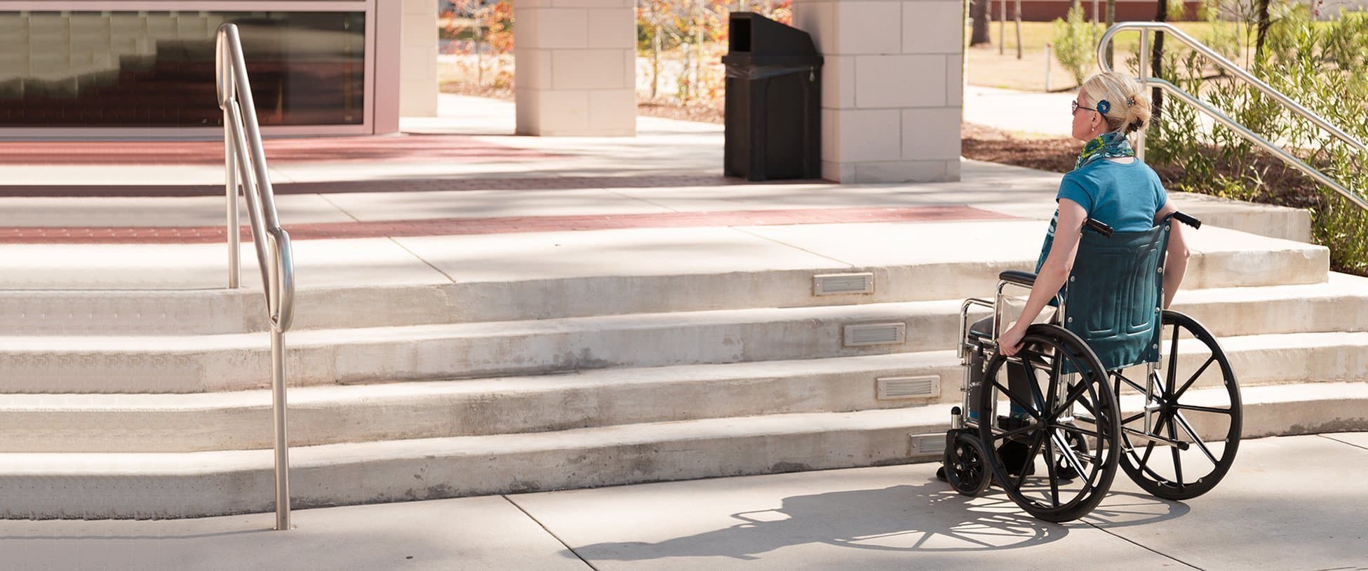 Woman in wheelchair in front of inaccessible stairs