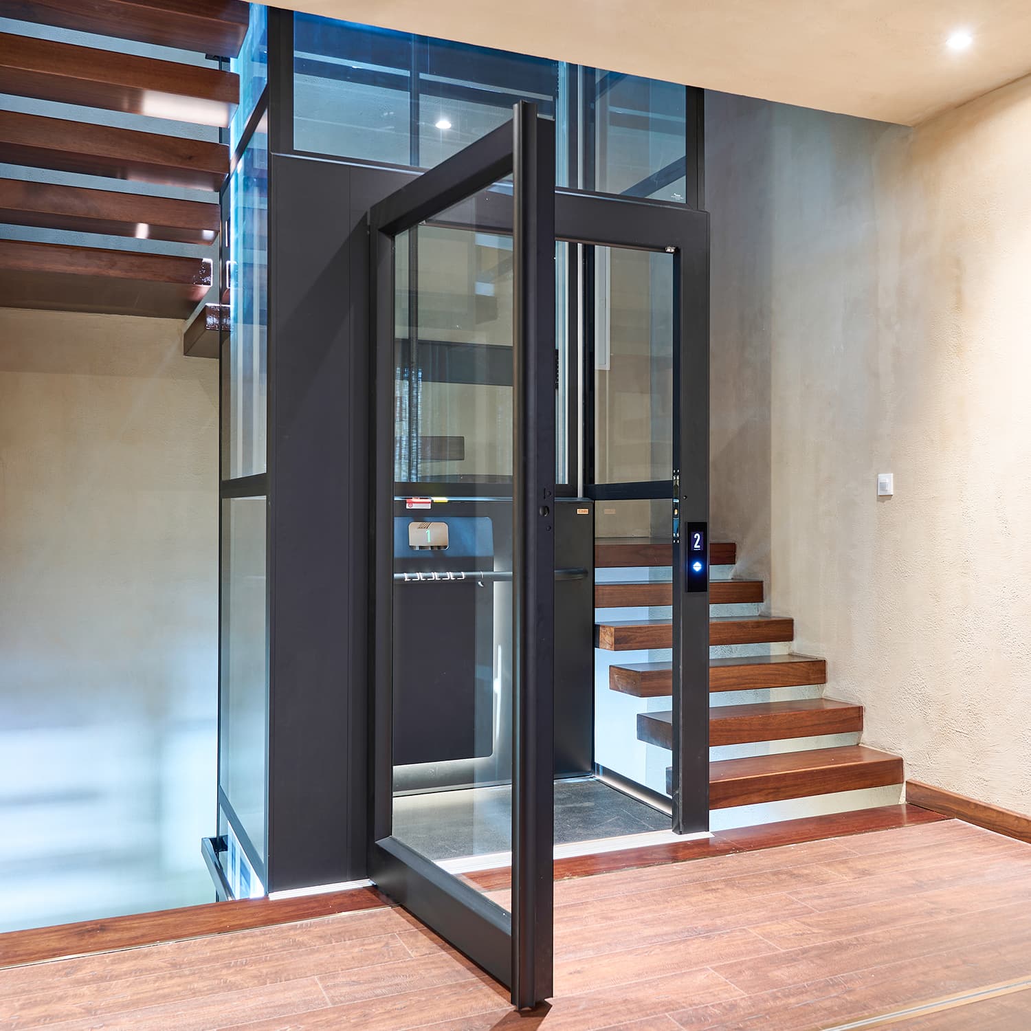 Black, glazed Cibes Air platform lift installed in a wooden staircase.