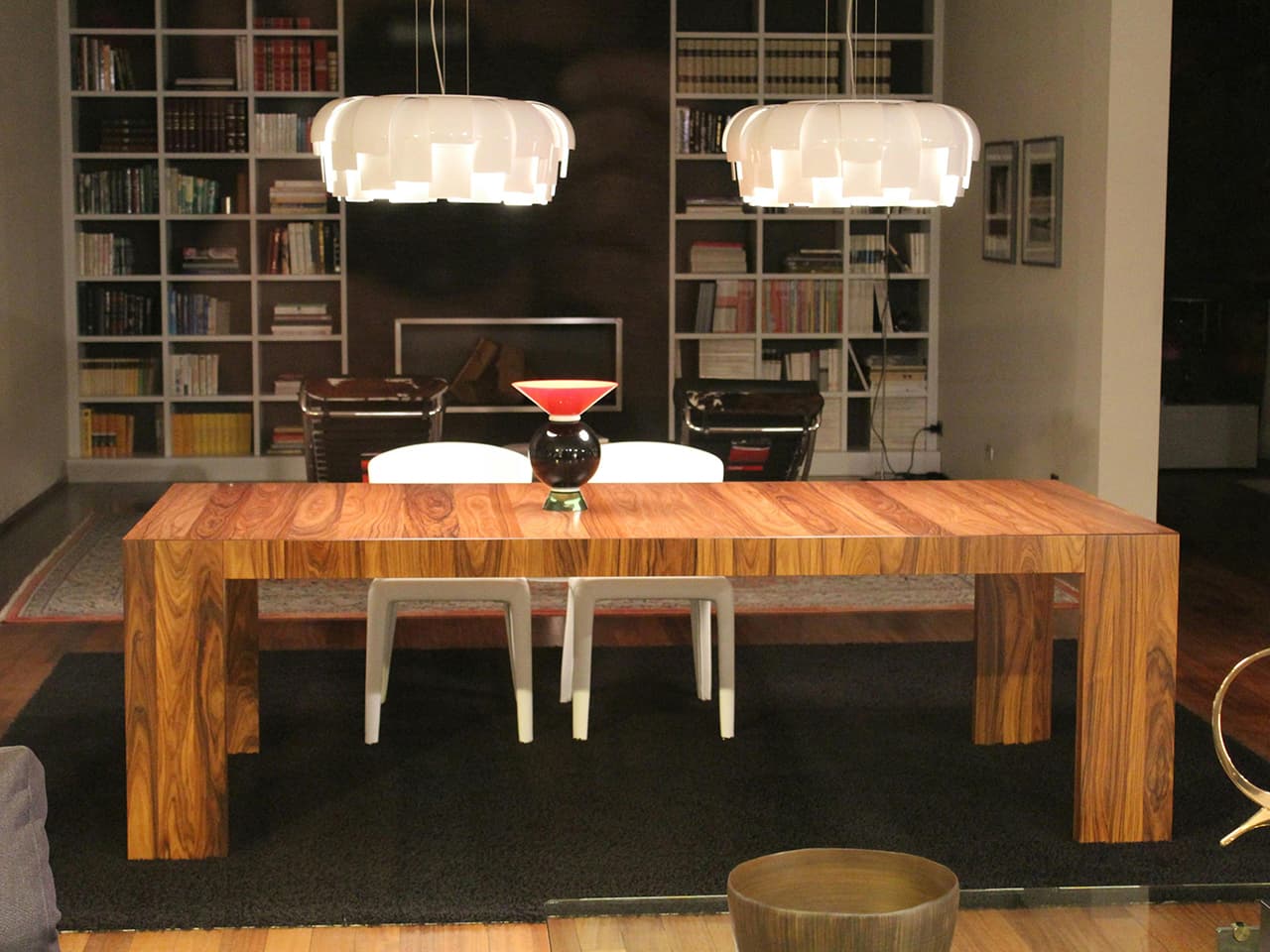 White, sculptural vintage pendants in nature inspired shapes above a chunky modern table in dark walnut wood.