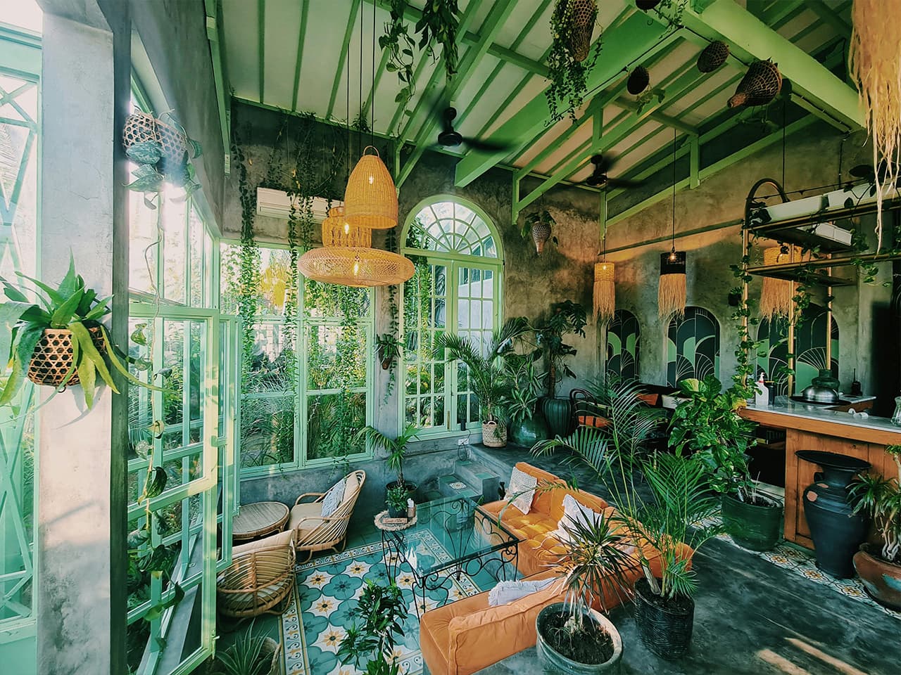Beautiful indoor orangerie style garden with potted plants and comfortable seating area. Light green orangerie windows.