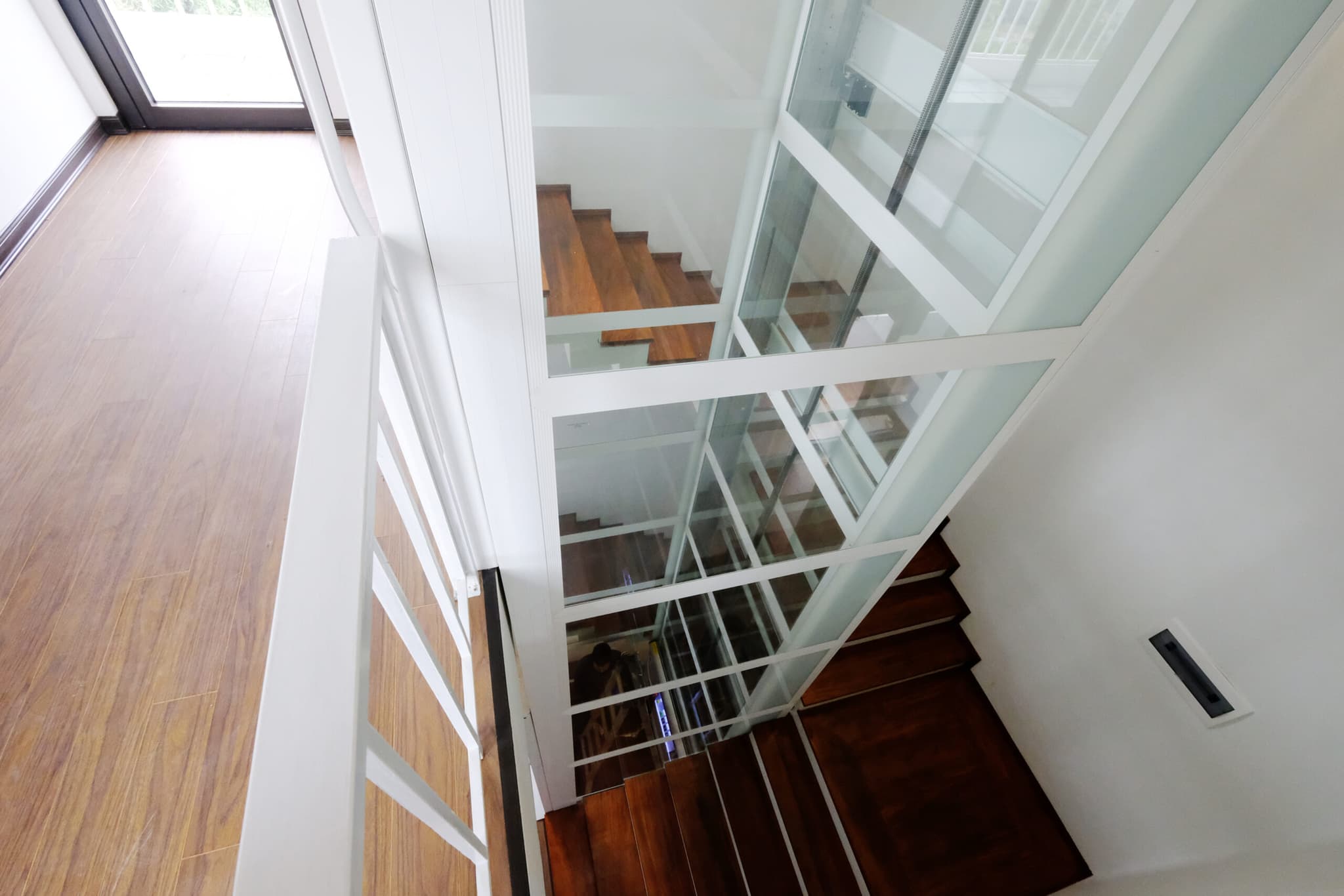 Fully glazed Cibes lift installed at the center of the staircase.